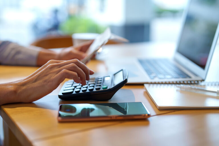 Cropped shot of Asian woman sitting at table doing financial plan and budget with calculator and laptop.