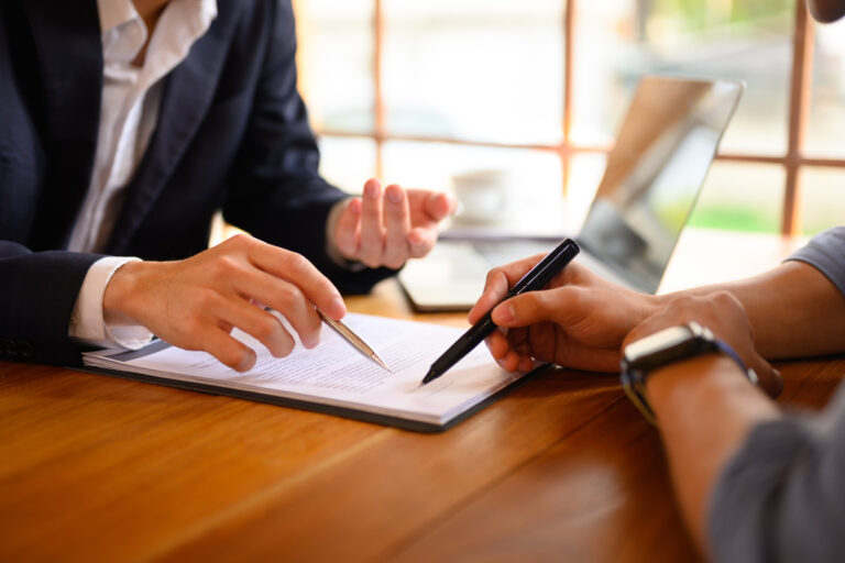 Closeup lawyer or insurance agent pointing at contract showing male client where to signature sign