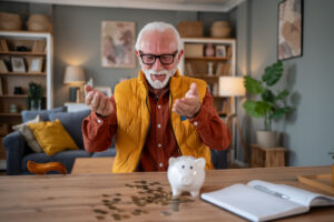 Man in vest at table with piggy bank and coins on table