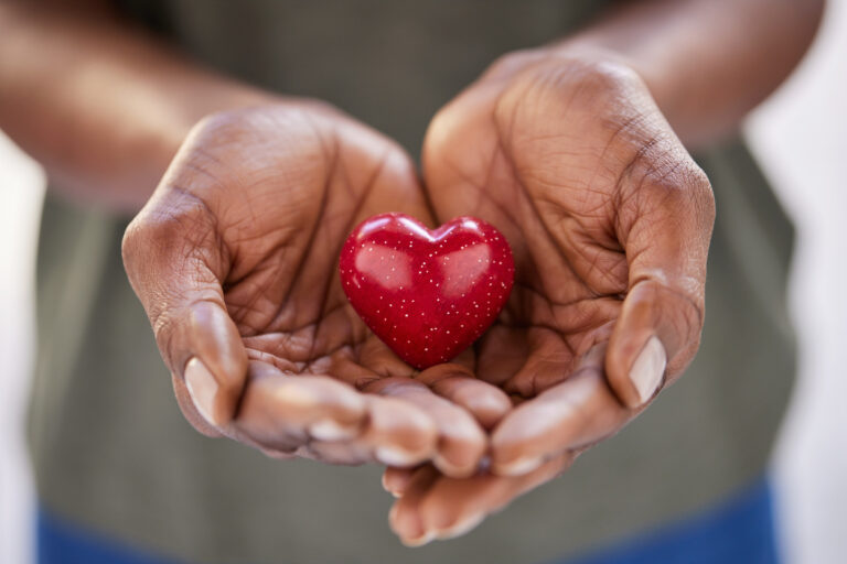 Close up of woman hands holding a small red heart.